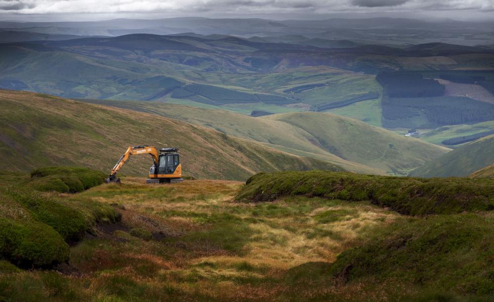 A lone excavator prevents ongoing erosion by reshaping peat gullies