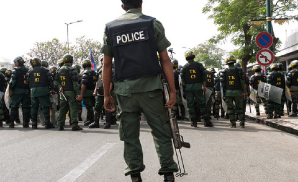 Police block a recent garment workers' protest in Phnom Penh. The police officer is holding a tear gas launcher. Photo: Luc Forsyth via Flickr.com.
