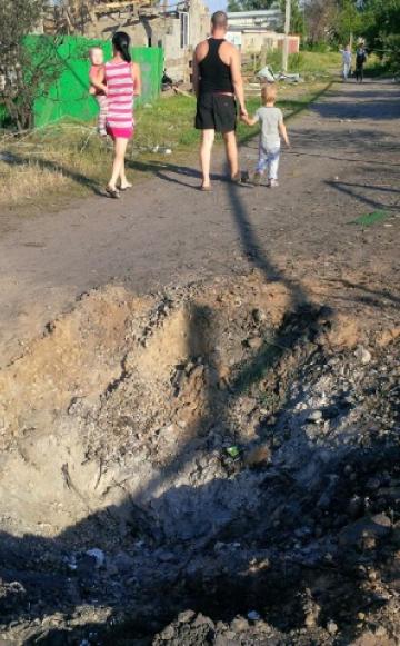 Family walking past a blast crater in Kandrashevka, where 9 civilians died during an aerial attack by alleged Ukranian forces on July 2, 2014. ©2014 Human Rights Watch.
