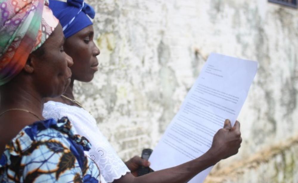 Deyeatee and Comfort, JogBahn Clan women leaders, reading the petition. Photo: Jason Taylor for Friends of the Earth, 2014.