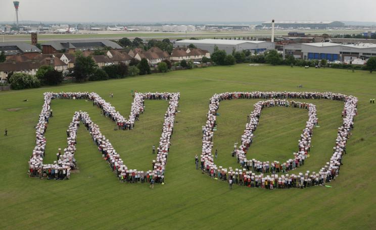 A group protest in a field in which a large crowd form the word 'NO' with their bodies