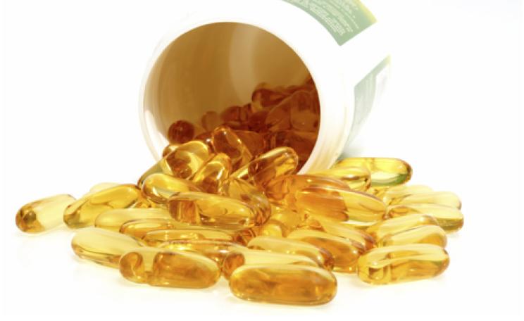 fish oil capsules spilling from a vitamin pill bottle