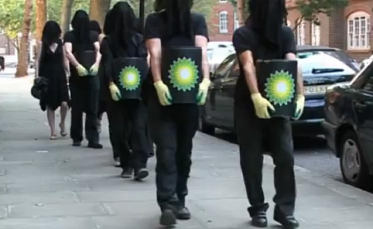 Protestors carry cans of 'oil' marked with BP logo
