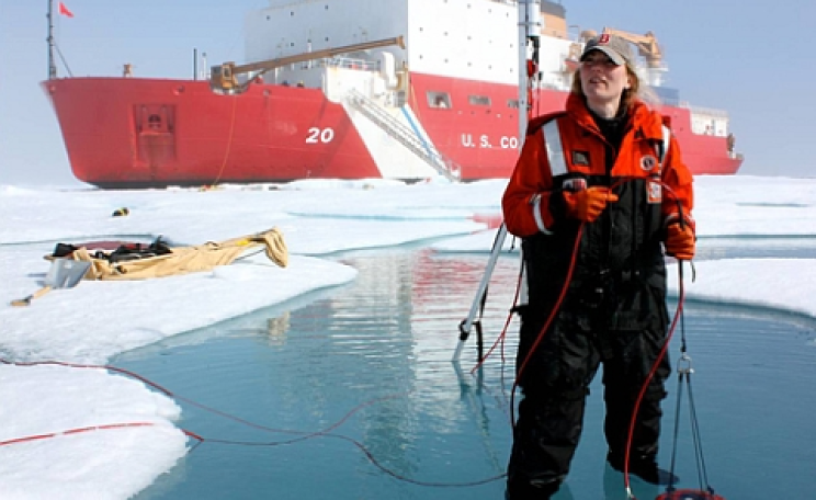 ICESCAPE scientist Karen Frey taking optical measurements in a melt pond, with US Coast Guard Cutter Healy. Photo: NASA's Goddard Space Flight Center / Kathryn Hansen.