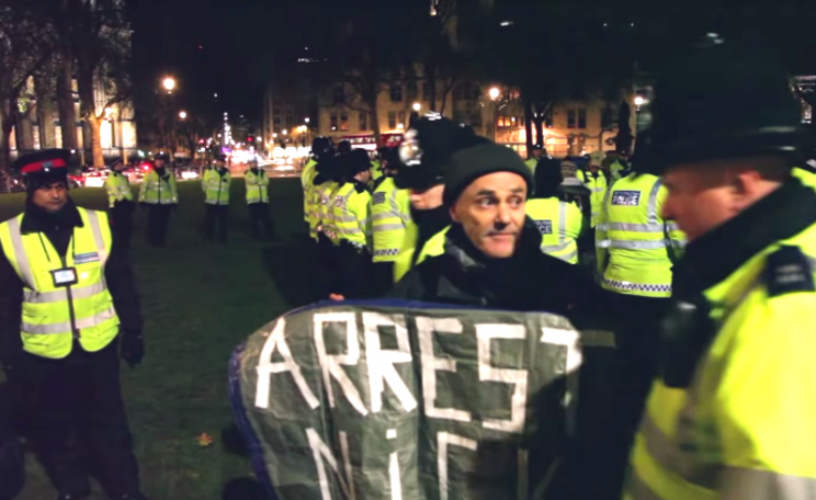 A policeman approaches Donnachadh McCarthy to arrest him in the middle of a media interview in Parliament Square, 19th December 2014. Photo: still from Youtube video by letmelooktv (embedded below).
